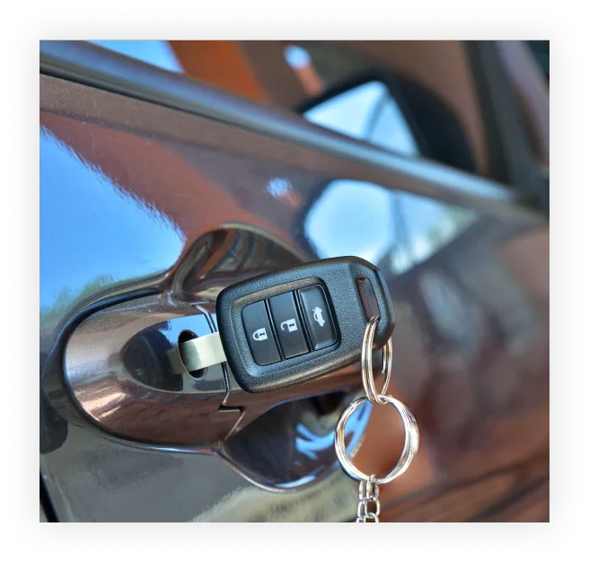Auto locksmith with a car key fob at a vehicle door in Queens